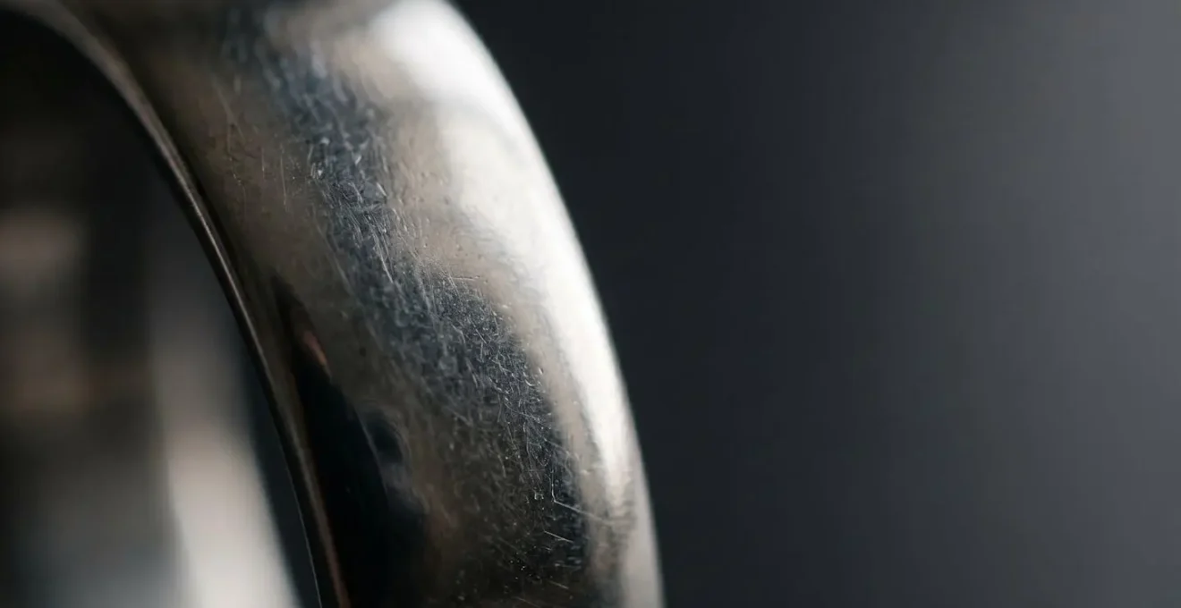 Gros plan artistique sur la surface d'un bijou en acier 316L montrant sa texture non-poreuse et sa brillance naturelle