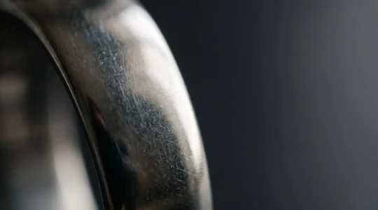Gros plan artistique sur la surface d'un bijou en acier 316L montrant sa texture non-poreuse et sa brillance naturelle
