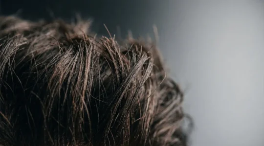 Gros plan sur des cheveux masculins épais et texturés coiffés avec de l'argile mate