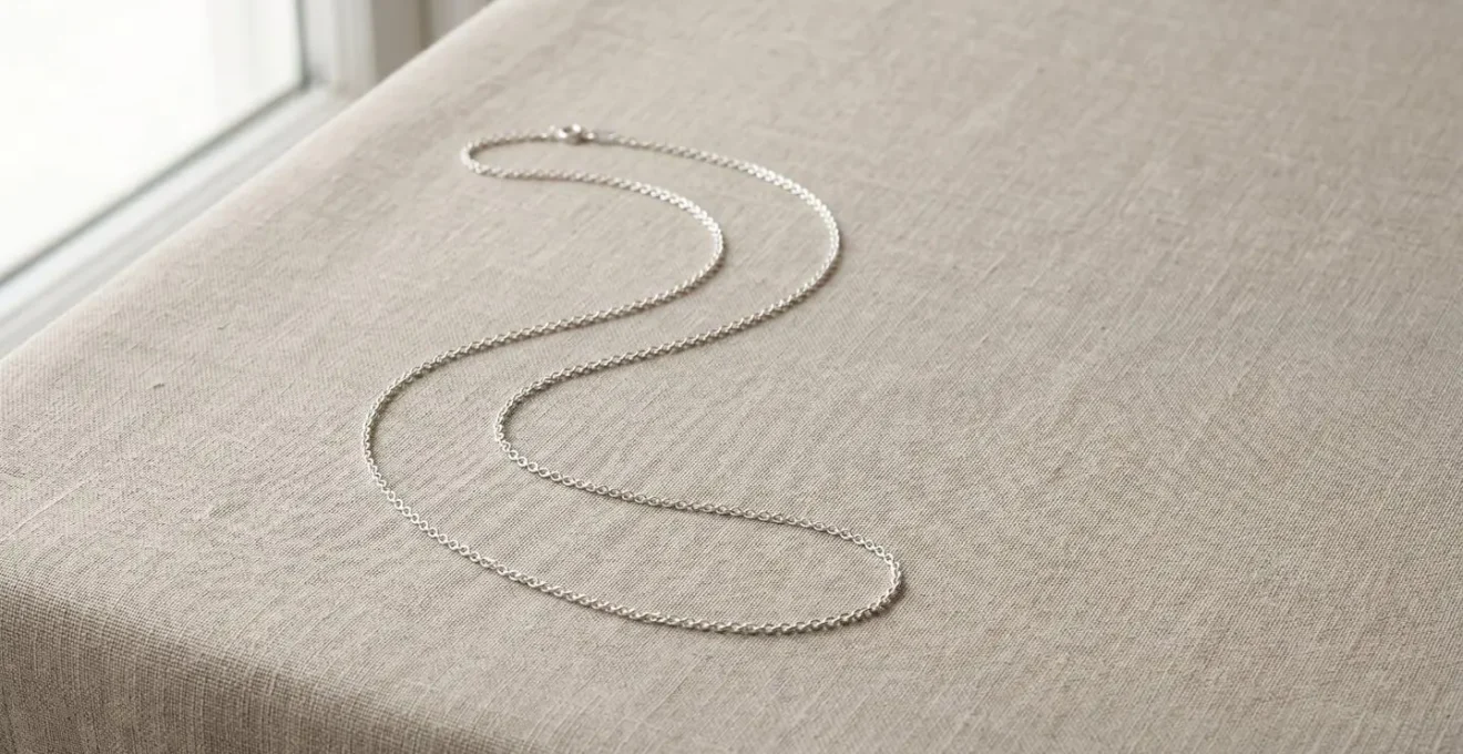 Chaîne en argent 925 étincelante disposée sur une surface minimaliste avec éclairage naturel doux