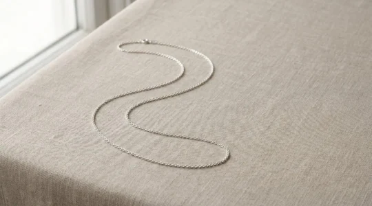 Chaîne en argent 925 étincelante disposée sur une surface minimaliste avec éclairage naturel doux