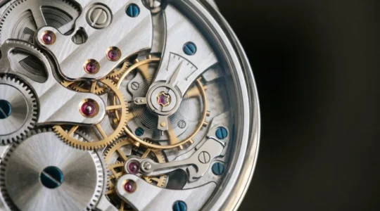 Gros plan sur un mouvement horloger squelette révélant la mécanique complexe et les finitions artisanales