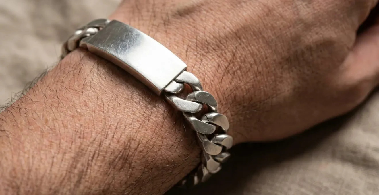 Gros plan d'une gourmette en argent au design épuré sur un poignet masculin, illustrant l'évolution du bijou traditionnel vers une esthétique contemporaine