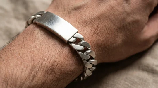 Gros plan d'une gourmette en argent au design épuré sur un poignet masculin, illustrant l'évolution du bijou traditionnel vers une esthétique contemporaine