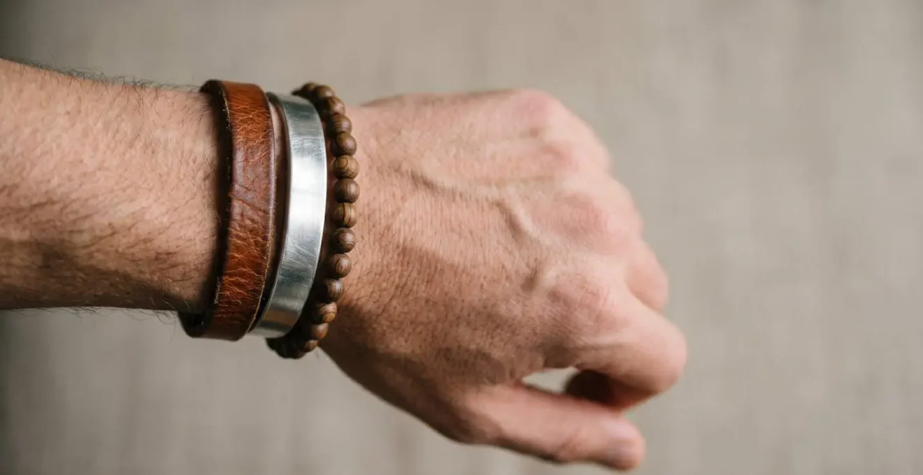 Gros plan sur un poignet masculin élégant portant trois bracelets empilés harmonieusement cuir métal et perles