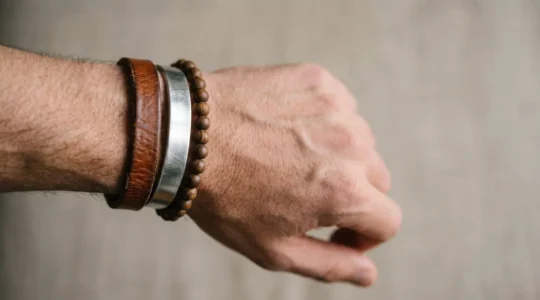 Gros plan sur un poignet masculin élégant portant trois bracelets empilés harmonieusement cuir métal et perles
